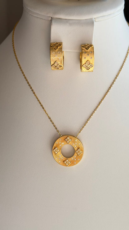 Gold jewelry set featuring a pendant necklace and matching hoop earrings displayed on a white mannequin bust. The jewelry has a textured gold finish with small clear stone accents.